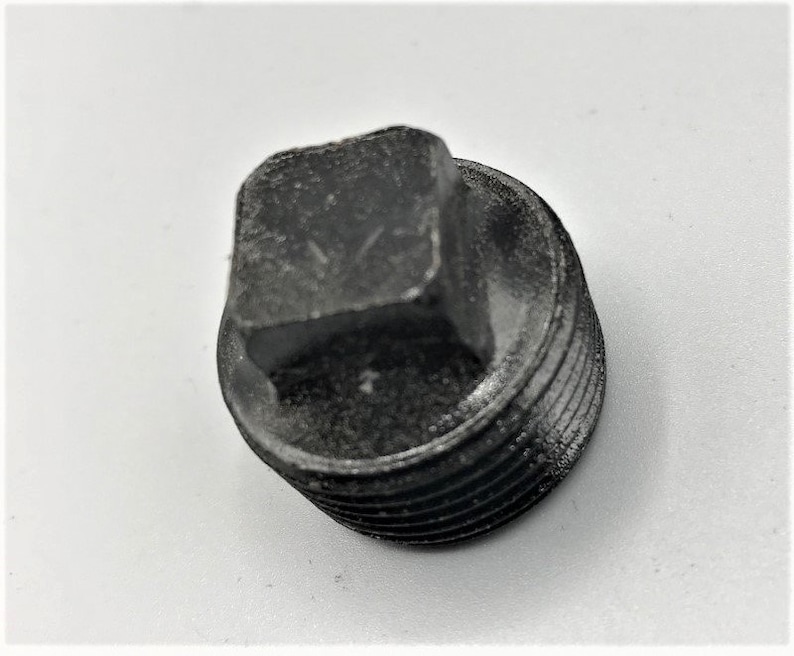 May include: A black metal pipe plug with a square head and a threaded body.