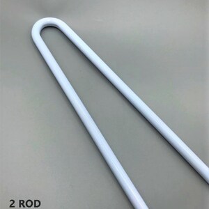 Puede incluir: Dos varillas de metal blanco, cada una doblada en forma de U. Las varillas se utilizan para sostener cortinas u otras cortinas.