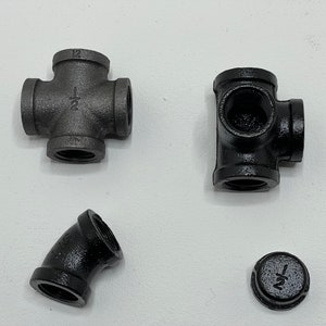 May include: Four black iron pipe fittings, including a cross, a tee, an elbow, and a cap. All fittings are 1/2 inch.