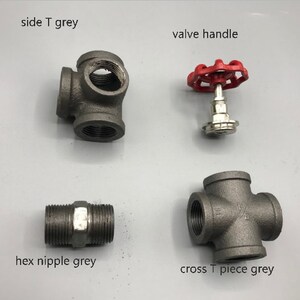 May include: Four plumbing fittings in grey metal, including a side T, a cross T, a hex nipple, and a valve handle with a red knob.