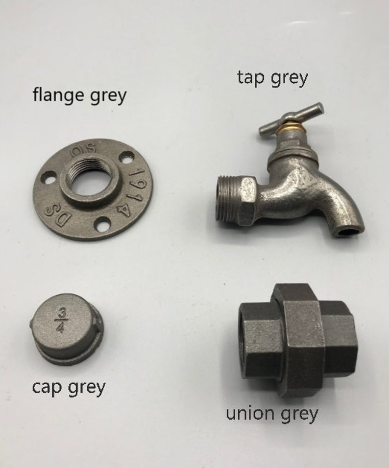 May include: A set of four grey metal plumbing fittings, including a flange, a cap, a union, and a tap. The flange is marked with the numbers "1 1/4" and "DS". The cap is marked with the fraction "3/4".
