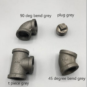May include: Four grey metal pipe fittings: a 90 degree bend, a 45 degree bend, a t-piece, and a plug.