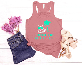 May include: A pink tank top with a graphic of a chinchilla wearing sunglasses and a palm tree. The text "Chinchillin' at the beach" is printed on the tank top.