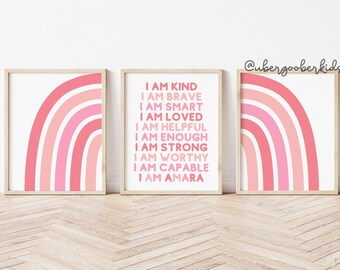 May include: Three framed prints with pink and white rainbow designs. The middle print has the text "I am kind, I am brave, I am smart, I am loved, I am helpful, I am enough, I am strong, I am worthy, I am capable, I am Amara".