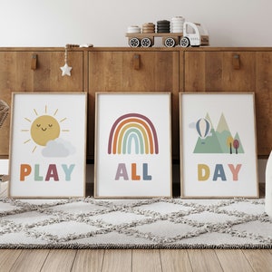 Puede incluir: Tres impresiones coloridas con ilustraciones y texto. La primera impresi&oacute;n presenta un sol amarillo con una cara sonriente y el texto "PLAY". La segunda impresi&oacute;n presenta un arco&iacute;ris con el texto "ALL". La tercera impresi&oacute;n presenta una cordillera verde con un globo aerost&aacute;tico y el texto "DAY".
