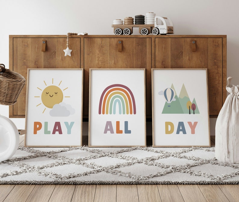 Puede incluir: Tres impresiones coloridas con ilustraciones y texto. La primera impresi&oacute;n presenta un sol amarillo con una cara sonriente y el texto "PLAY". La segunda impresi&oacute;n presenta un arco&iacute;ris con el texto "ALL". La tercera impresi&oacute;n presenta una cordillera verde con un globo aerost&aacute;tico y el texto "DAY".
