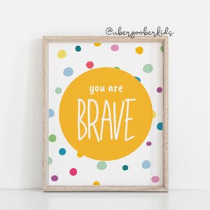 May include: A yellow circle with the text "you are BRAVE" on a white background with colourful polka dots.