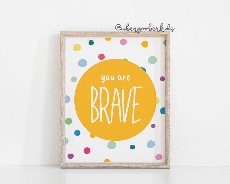 May include: A yellow circle with the text "you are BRAVE" on a white background with colourful polka dots.