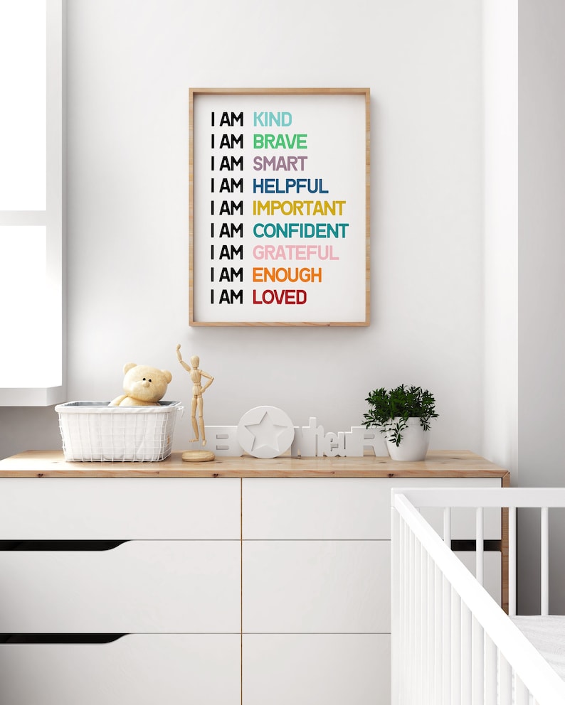 May include: A framed print with the text "I AM" followed by a list of positive affirmations in different colors, including "KIND", "BRAVE", "SMART", "HELPFUL", "IMPORTANT", "CONFIDENT", "GRATEFUL", "ENOUGH", and "LOVED".