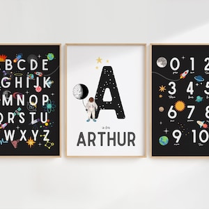 May include: Three black framed prints with a space theme. The first print features the alphabet with space-themed illustrations. The second print features the letter A with a spaceman and the name Arthur. The third print features numbers 1-10 with space-themed illustrations.