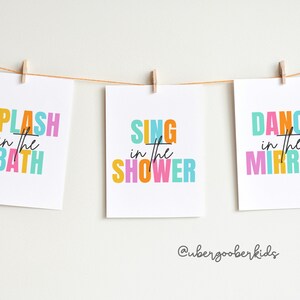 May include: Three colorful printable wall art prints with the text "Splash in the Bath", "Sing in the Shower", and "Dance in the Mirror".