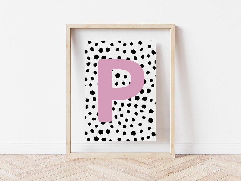 May include: A framed print featuring a black and white polka dot pattern with a large pink letter "P" in the centre.