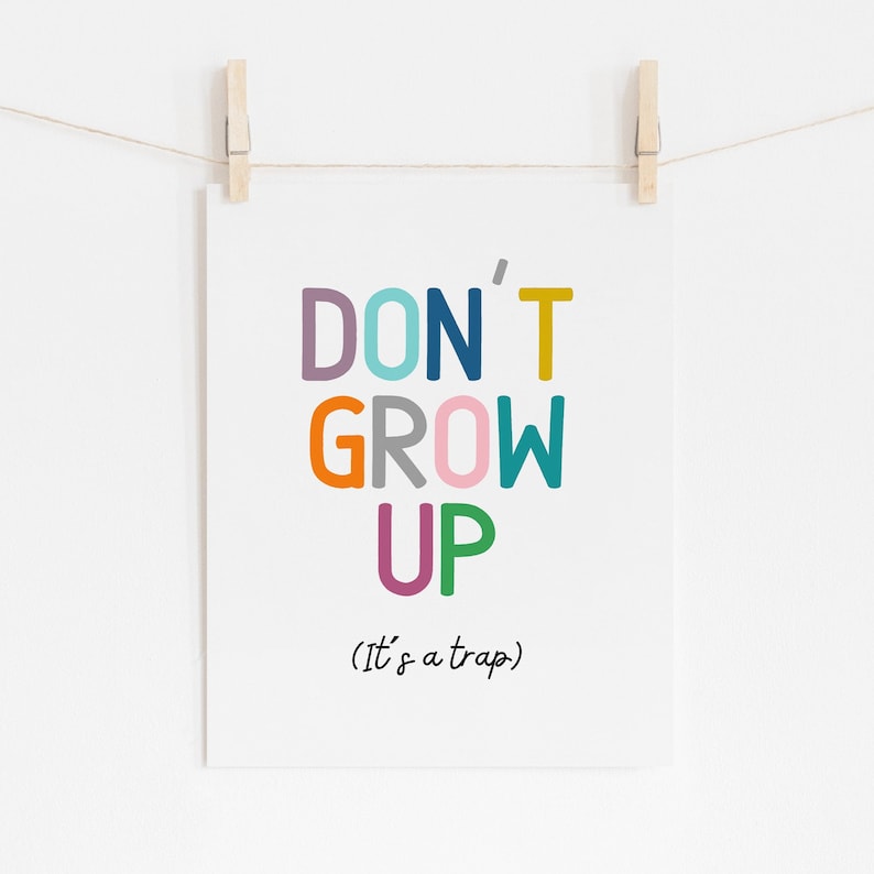 May include: A colorful print with the text "DON'T GROW UP (It's a trap)" in a playful font. The words are in different colors, including purple, blue, teal, yellow, orange, gray, pink, and green.