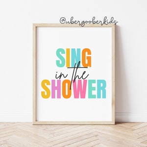 May include: A colorful print with the text "SING in the SHOWER" in a white frame. The text is in a rainbow of colors, including yellow, orange, pink, blue, and green.