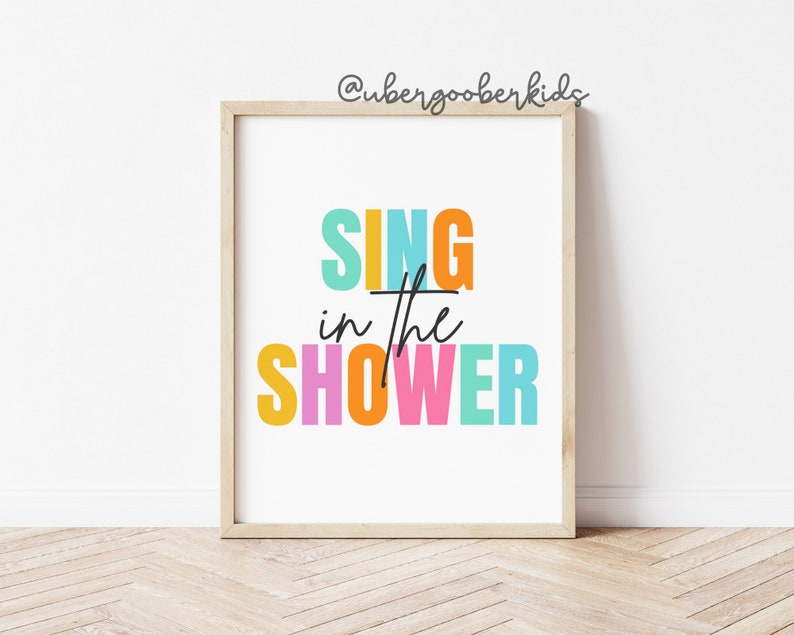 May include: A colorful print with the text "SING in the SHOWER" in a white frame. The text is in a rainbow of colors, including yellow, orange, pink, blue, and green.