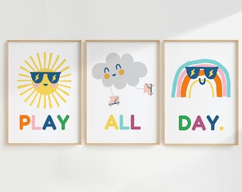 May include: Three colorful prints with illustrations of a sun, a cloud, and a rainbow, each wearing sunglasses. The text "PLAY ALL DAY." is written below the illustrations.