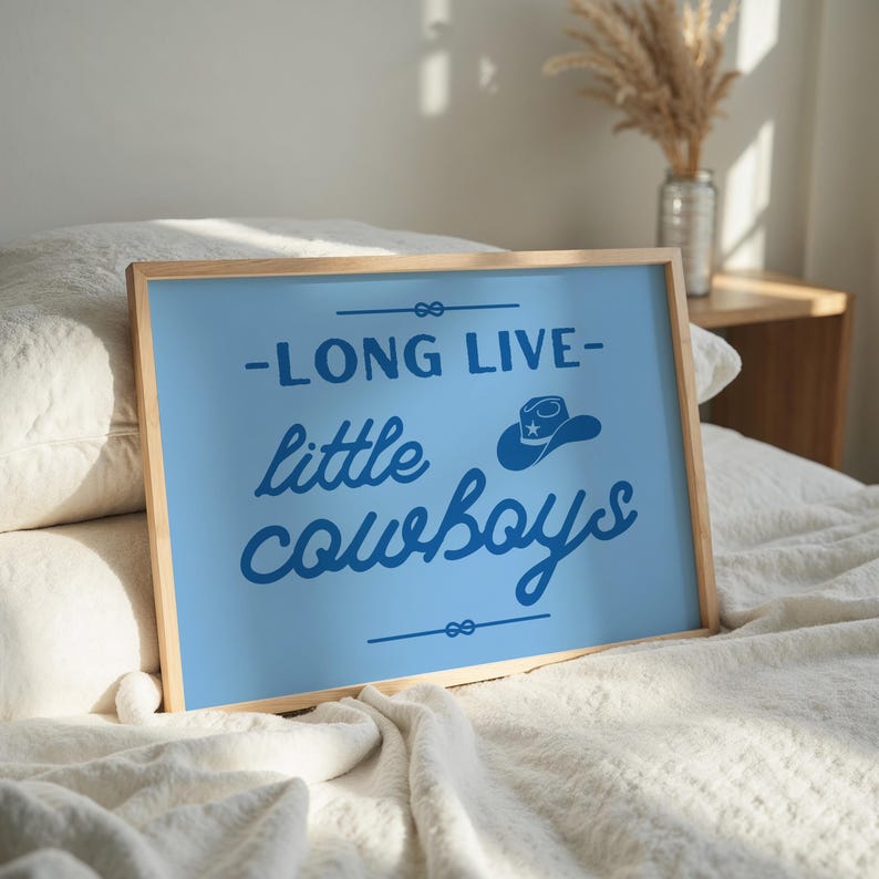 May include: A blue framed print with the text "Long Live Little Cowboys" in a blue script font. A blue cowboy hat with a white star is above the text.