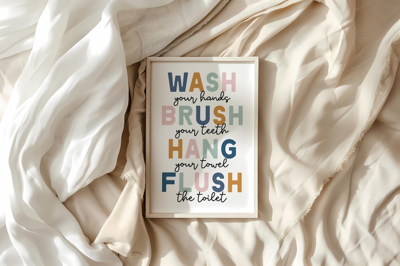 May include: A framed bathroom art print with the words "WASH your hands, BRUSH your teeth, HANG your towel, FLUSH the toilet" in colorful block letters. The print is set against a neutral background.