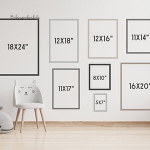 May include: A white wall with nine different sized picture frames, each with a different size measurement written inside. The measurements are in inches. The frames are arranged in a grid pattern. There is a white chair with cat ears in the lower left corner of the image.