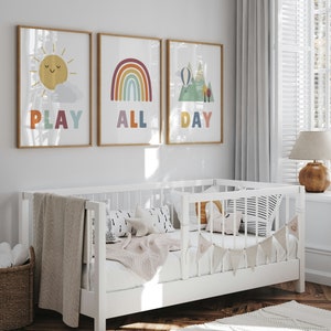 Puede incluir: Tres impresiones enmarcadas con ilustraciones y texto coloridos. La primera impresi&oacute;n presenta un sol amarillo con una cara sonriente y el texto "PLAY". La segunda impresi&oacute;n presenta un arco&iacute;ris con el texto "ALL". La tercera impresi&oacute;n presenta una cordillera con un globo aerost&aacute;tico y el texto "DAY".