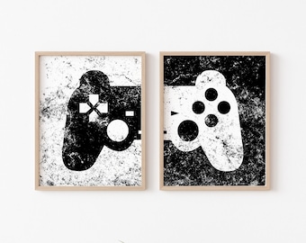 May include: Two black and white framed prints of video game controllers. The left print has a white controller on a black background. The right print has a black controller on a white background.