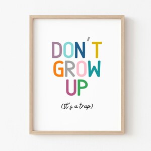 May include: A framed print with the text "DON'T GROW UP (It's a trap)" in colorful letters. The letters are in different colors, including pink, orange, blue, green, and purple.