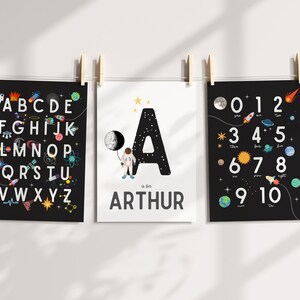 May include: Three black and white posters with a space theme. The first poster features the alphabet with space-themed illustrations. The second poster features the letter A with a spaceman holding a moon. The third poster features the numbers 0-10 with space-themed illustrations. The second poster also includes the name "Arthur".