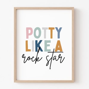 May include: A framed print with the text "Potty Like A Rock Star" in colorful letters. The letters are in shades of pink, blue, green, yellow, and gray. The text "rock star" is written in black cursive.