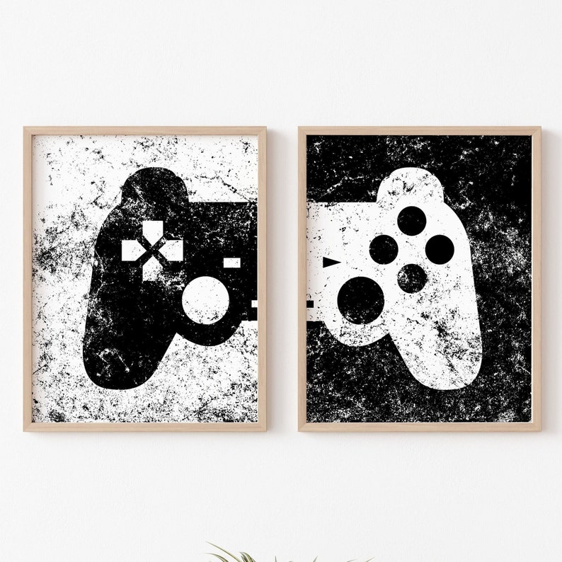 May include: Two black and white framed prints of video game controllers with a distressed, grunge-style design.