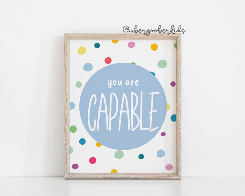 May include: A light blue framed print with a white background and colourful polka dots. The print features a large light blue circle with the text "you are CAPABLE" in white.