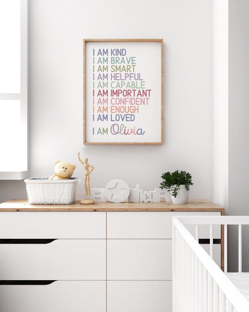 May include: A framed print with a white background and colorful text that reads "I am kind, I am brave, I am smart, I am helpful, I am capable, I am important, I am confident, I am enough, I am loved, I am Olivia".