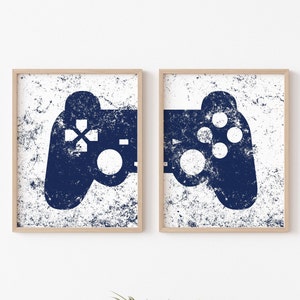 Peut inclure: Deux impressions encadrées de manettes de jeu vidéo bleues sur un mur blanc. Les manettes sont dans un style vintage et détérioré.