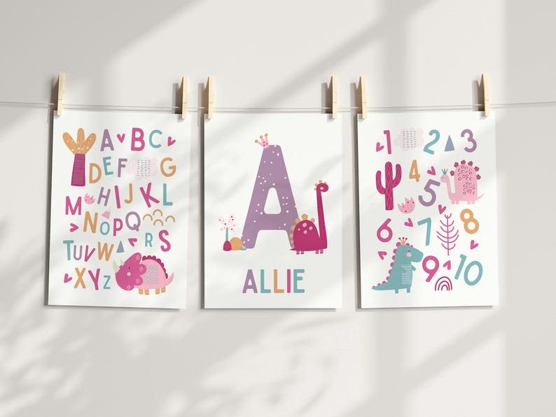 Puede incluir: Tres impresiones de arte de pared imprimibles con un tema de dinosaurio rosa y morado. La primera impresi&oacute;n muestra el alfabeto con un dinosaurio rosa. La segunda impresi&oacute;n muestra la letra A con un dinosaurio rosa y el nombre Allie. La tercera impresi&oacute;n muestra los n&uacute;meros del 1 al 10 con un dinosaurio rosa y un dinosaurio azul.