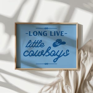 May include: A blue framed print with the text "Long Live Little Cowboys" in white lettering. A small blue cowboy hat with a white star is above the text.