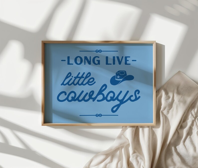 May include: A blue framed print with the text "Long Live Little Cowboys" in white lettering. A small blue cowboy hat with a white star is above the text.