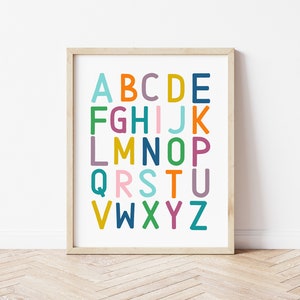 Puede incluir: Una impresi&oacute;n de alfabeto enmarcada con letras coloridas sobre un fondo blanco. Las letras est&aacute;n en una fuente en negrita y juguetona. El marco es de madera clara.