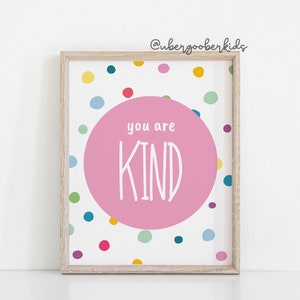 May include: A framed print with a pink circle in the centre that says "you are KIND" in white text. The background is white with a colourful confetti pattern.
