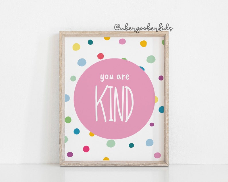 May include: A framed print with a pink circle in the centre that says "you are KIND" in white text. The background is white with a colourful confetti pattern.
