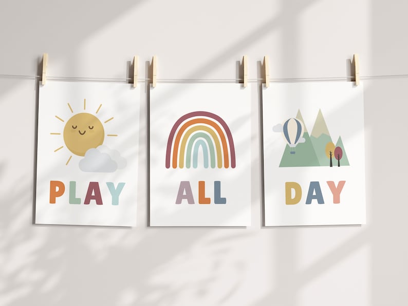 Puede incluir: Tres impresiones coloridas con ilustraciones de un sol, un arco&iacute;ris y monta&ntilde;as con un globo aerost&aacute;tico. El texto en las impresiones dice "PLAY ALL DAY".