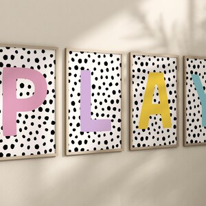 May include: Four framed prints with a black and white polka dot background and large colourful letters spelling out the word "PLAY". The letters are pink, purple, yellow, and blue.