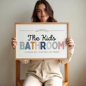 May include: A framed sign with the text "WARNING The Kids BATHROOM (I HAVE NO CONTROL IN HERE)". The sign has a light wood frame and the text is in various colors including black, blue, and pink.