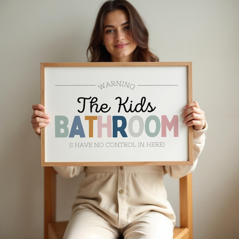 May include: A framed sign with the text "WARNING The Kids BATHROOM (I HAVE NO CONTROL IN HERE)". The sign has a light wood frame and the text is in various colors including black, blue, and pink.