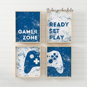 May include: Four blue and white framed prints with a gamer theme. The prints feature the text "Gamer Zone", "Ready Set Play", and a white video game controller on a blue background.
