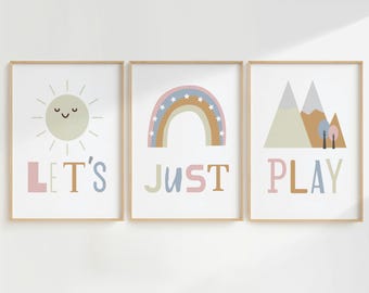 May include: Three framed prints with a minimalist design. The first print features a yellow sun with a smiling face and the text "LET'S". The second print features a rainbow with stars and the text "JUST". The third print features a mountain range with trees and the text "PLAY".