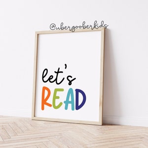 May include: A framed print with the text "let's READ" in colorful letters. The letters are in shades of orange, yellow, green, blue, and purple. The background is white.