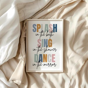 以下が含まれることがあります： 白い背景にカラフルな文字で「SPLASH in the bath SING in the shower DANCE in the mirror」と書かれた額装されたプリントです。