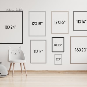 May include: A white wall with nine different sized picture frames, each with a different size measurement written inside. The measurements are in inches. The frames are arranged in a grid pattern. There is a white chair with cat ears in the lower left corner of the image.