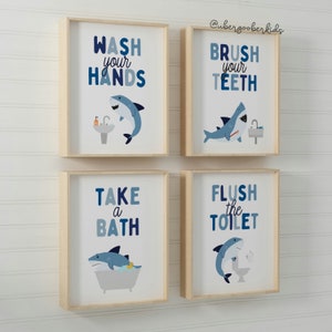May include: Four framed prints with blue and white shark illustrations and bathroom-themed text. The prints read "Wash your hands", "Brush your teeth", "Take a bath", and "Flush the toilet".