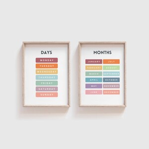 May include: Two framed prints with a white background and colorful text. The left print says "DAYS" and lists the days of the week in a rainbow color scheme. The right print says "MONTHS" and lists the months of the year in a rainbow color scheme.