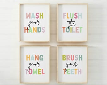 May include: Four colorful bathroom signs with a white background and a light wood frame. The signs read "Wash your hands", "Flush the toilet", "Hang your towel", and "Brush your teeth".